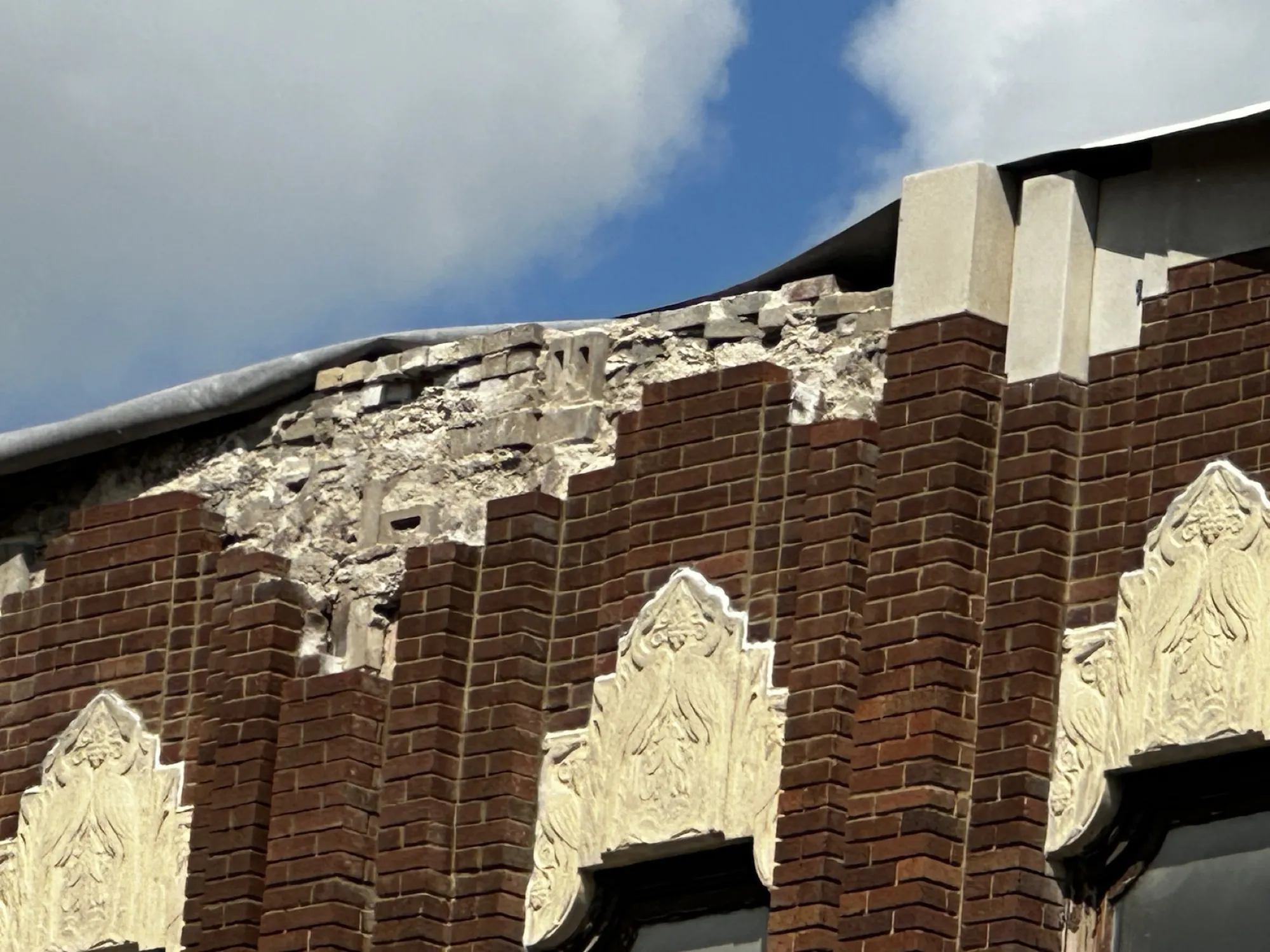 Sections of cast stone had already fallen to the sidewalk, triggering a building department violation.